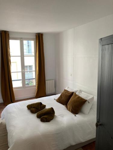 un grand lit blanc avec trois chiens allongés dessus dans l'établissement L'atelier du château, à Versailles