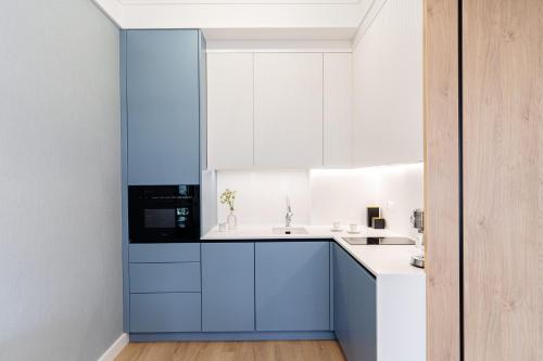 a kitchen with blue and white cabinets and a sink at Sol Marina Resort Wyspa Sobieszewska II - LoftAffair Collection in Wiślinka
