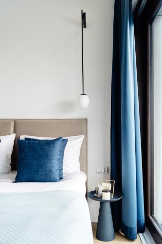 a bedroom with a bed and a blue curtain at Sol Marina Resort Wyspa Sobieszewska II - LoftAffair Collection in Wiślinka