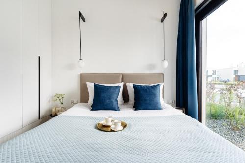a bedroom with a large bed with blue pillows at Sol Marina Resort Wyspa Sobieszewska II - LoftAffair Collection in Wiślinka