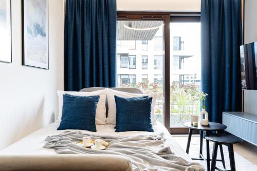 a bedroom with a bed with blue curtains and a window at Sol Marina Resort Wyspa Sobieszewska II - LoftAffair Collection in Wiślinka