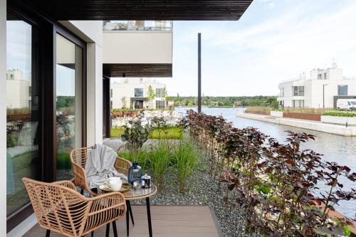 a table and chairs on a balcony with a view of the water at Sol Marina Resort Wyspa Sobieszewska II - LoftAffair Collection in Wiślinka