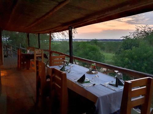 a dinner table with a view of a field at Hornbill Bush Lodge in Pakwach East