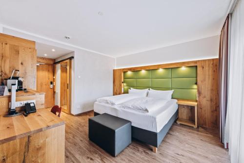 a bedroom with a large bed with a green headboard at Obermühle 4*S Boutique Resort in Garmisch-Partenkirchen