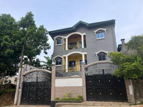 a large house with a black gate in front of it at DOM city Chambre meublée Pink in Douala