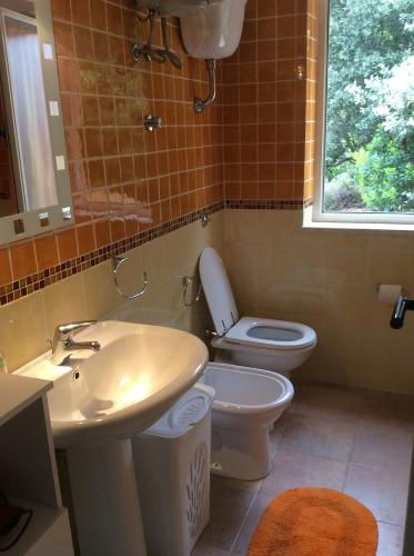 a bathroom with a sink and a toilet and a window at Villetta Vista Mare in Costa Paradiso