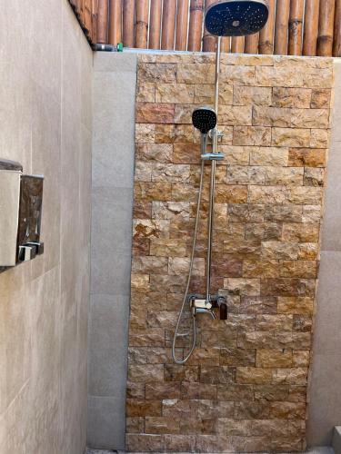 a shower in a bathroom with a stone wall at Living Trawangan Hotel in Gili Trawangan