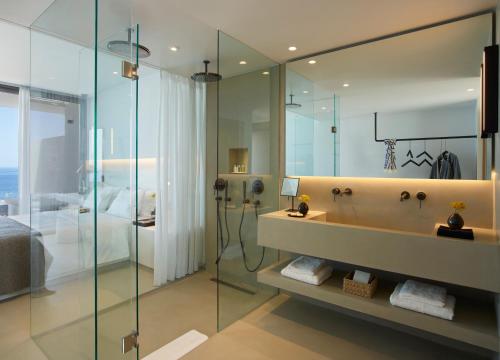 a bathroom with a tub and a glass shower at Domes White Coast Milos, Adults Only - Small Luxury Hotels of the World in Mytakas