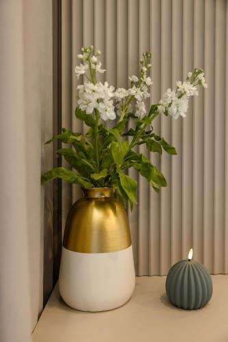 a gold and white vase with white flowers on a table at Apartament LUNA z jacuzzi Premium na Mazurach in Ełk