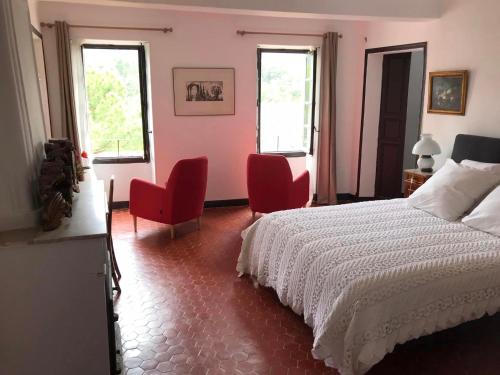 a bedroom with a bed and two red chairs at La Maison Joly in Ménerbes