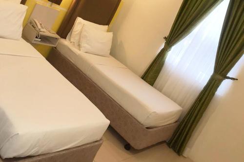 two beds in a hotel room with a window at Cebu Uncle Toms Cabin Hotel powered by Cocotel in Cebu City