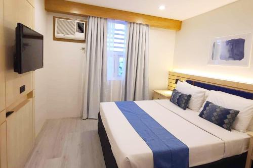 a hotel room with a bed and a television at Cebu Uncle Toms Cabin Hotel powered by Cocotel in Cebu City