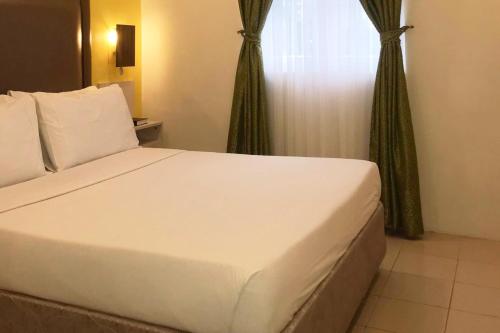 a white bed in a room with a window at Cebu Uncle Toms Cabin Hotel powered by Cocotel in Cebu City