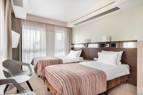 a hotel room with two beds and a chair at Hotel Arkon Park Gdańsk- Destigo Hotels in Gdańsk