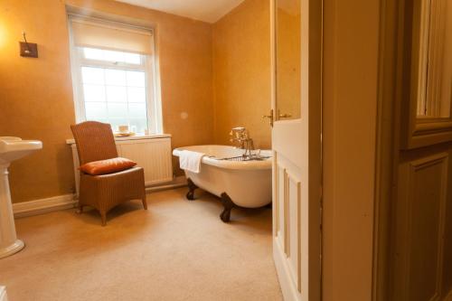 a bathroom with a tub and a chair and a window at Meifod House in Caernarfon