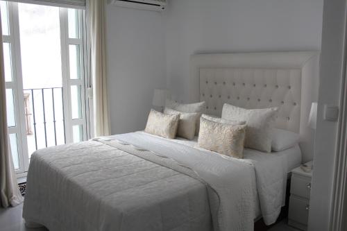 a white bedroom with a large white bed with pillows at Panther Home Sierpes in Seville