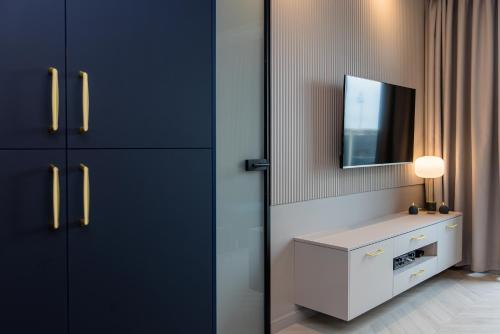 a bathroom with black cabinets and a tv on the wall at Apartament LUNA z jacuzzi Premium na Mazurach in Ełk