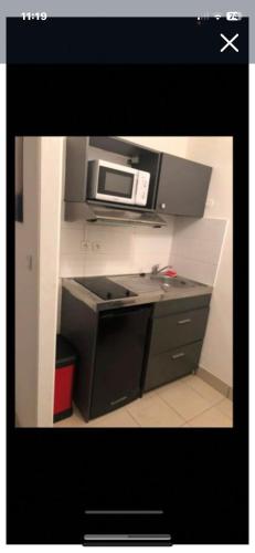 une cuisine avec une cuisinière et un micro-ondes dans l'établissement Studio en rez de jardin, à Carry-le-Rouet