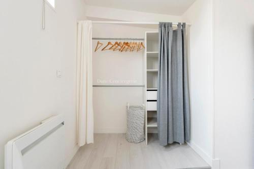 un dressing avec des murs blancs et des rideaux gris dans l'établissement Coeur des Chartrons, à Bordeaux