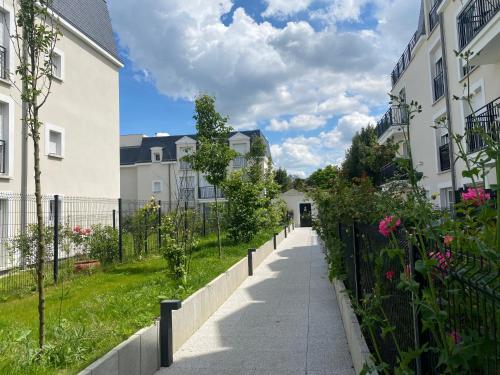 a sidewalk in front of some buildings with flowers at Le chic de Villiers Sur Marne in Villiers-sur-Marne