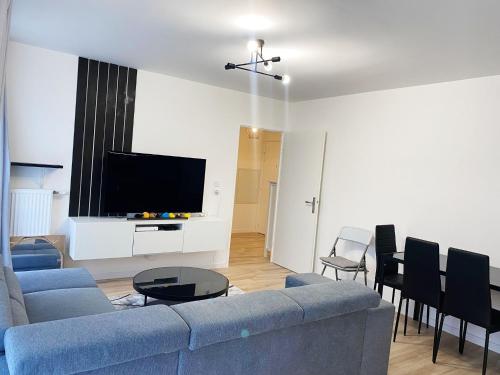 a living room with a blue couch and a flat screen tv at Le chic de Villiers Sur Marne in Villiers-sur-Marne