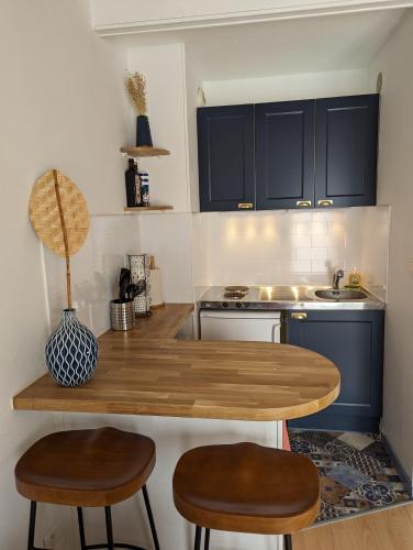 une cuisine avec une table en bois et deux tabourets dans l'établissement Duplex marin à La Rochelle, à La Rochelle