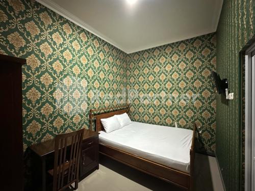 a small bed in a room with green wallpaper at Salim Living RedPartner in Lawean