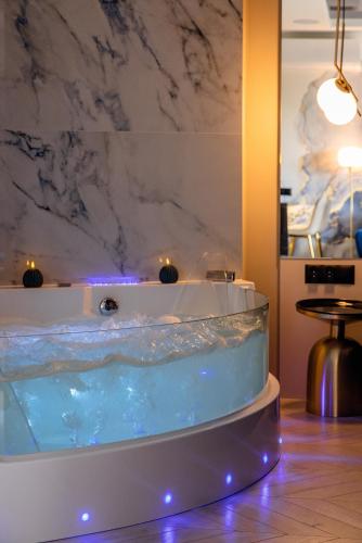 a jacuzzi tub in a room with a marble wall at Apartament LUNA z jacuzzi Premium na Mazurach in Ełk