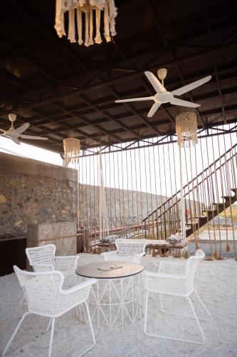 a patio with white chairs and a table and ceiling fans at Sangam Farms in Bhilwara