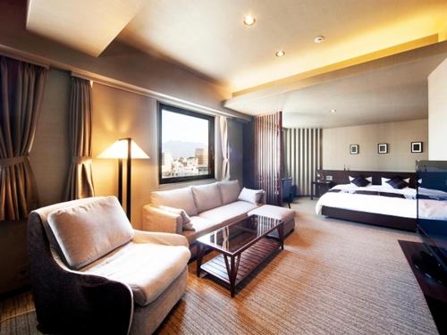 a hotel room with a bed and a living room at Silk Inn Kagoshima in Kagoshima