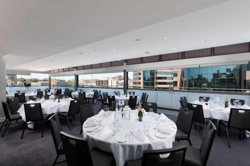 a restaurant with white tables and chairs and windows at Rydges Sydney Central in Sydney