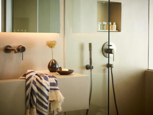a bathroom with a table with a vase on it at Domes White Coast Milos, Adults Only - Small Luxury Hotels of the World in Mytakas