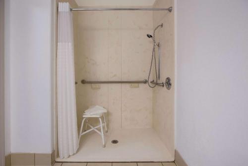 a shower with a shower curtain and a stool in a bathroom at Country Inn & Suites by Radisson, Marion, IL in Marion