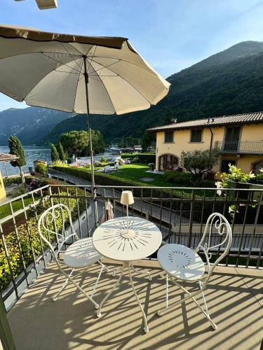 three chairs and a table and an umbrella on a balcony at Alex's lake house in Riva di Solto