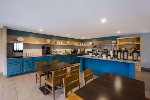 a kitchen with blue cabinets and wooden tables and chairs at Country Inn & Suites by Radisson, Marion, IL in Marion