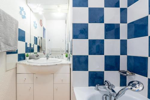 La salle de bains bleue et blanche est pourvue d'un lavabo et d'une baignoire. dans l'établissement Le Nid des Marmottes - Appt proche station de ski, à Villarembert