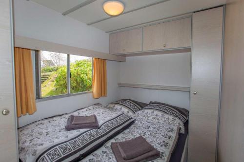 a small bedroom with a bed and a window at Bungalow Sun am See in Zirkow