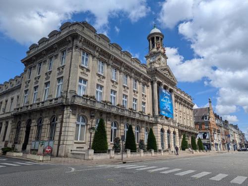 a large building with a clock tower on a street at Les Bêtises, Duplex Hyper-centre in Cambrai