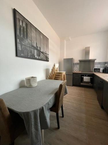 une cuisine avec une table et des chaises ainsi qu'une cuisine avec une cuisinière dans l'établissement La Léonce, superbe appartement plein centre, à Armentières