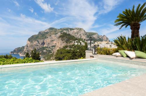une piscine avec une montagne en arrière-plan dans l'établissement Villa Hibiscus, à Capri