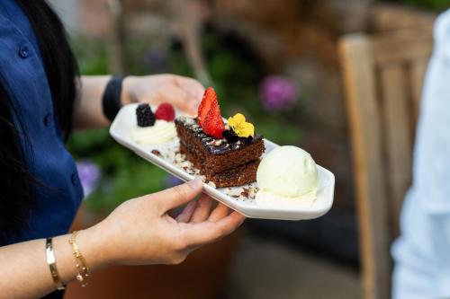 a person holding a plate of cake and ice cream at Merton Hotel in St. Saviour