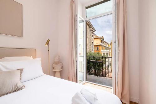 a bedroom with a white bed and a large window at Soleil de la Buffa - Un joyau central à 3 min des plages in Nice