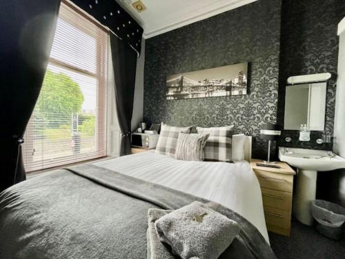 a bedroom with a large bed and a sink at Vaila Guest House in Aberdeen