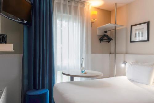 a hotel room with a bed and a window at Hôtel Kyriad Dieppe in Saint-Aubin-sur-Scie