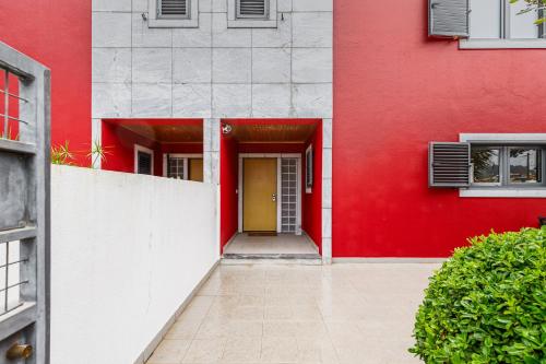 a red and white building with a yellow door at Casa das Fontes - House of Wells in Parede