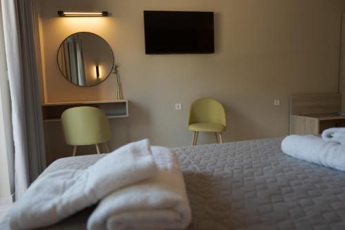 a bedroom with a bed and a mirror and two chairs at The Mark Hotel in Gliki