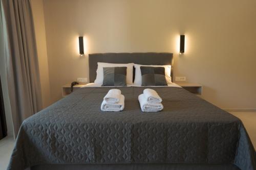 a bedroom with a bed with two white slippers on it at The Mark Hotel in Gliki