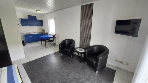 a room with two chairs and a table and a tv at Pension Mosella , Wohnung mit Balkon und Moselblick in Sankt Aldegund