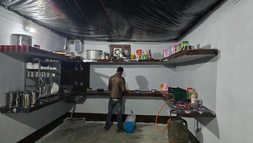 a man standing at a counter in a room at Sangla Valley Camping in Saturang