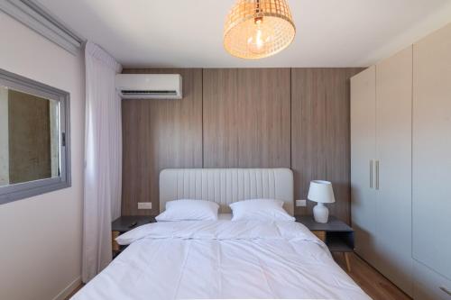 a bedroom with a large white bed and a chandelier at Eilat Luxury Vacation -Amazing Pool in Eilat